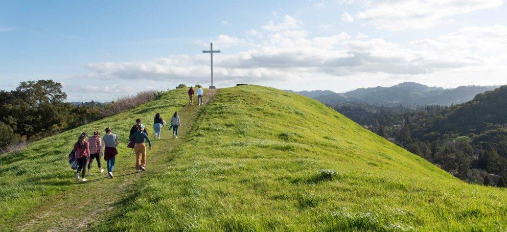 Students hiking to a cross on a hill together